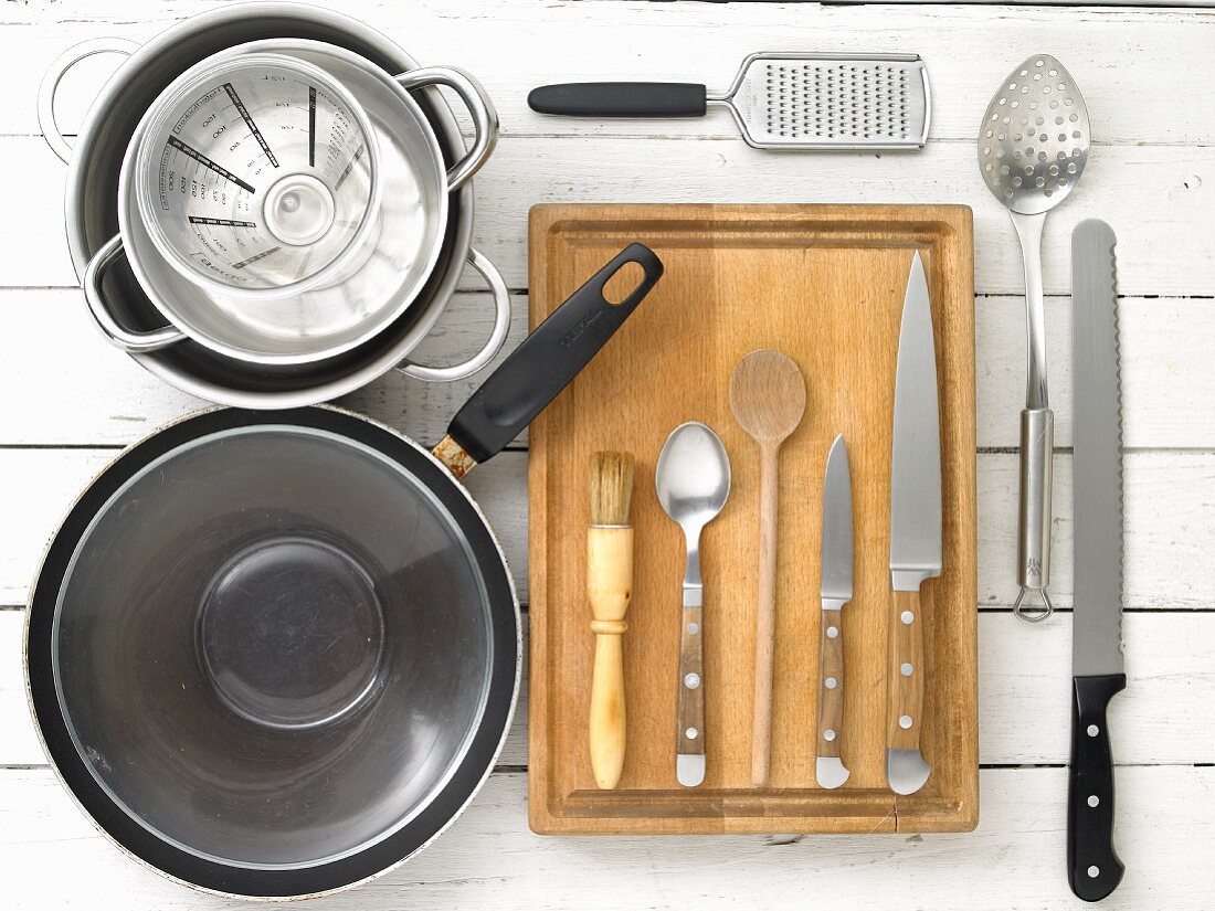 Küchenutensilien: Pfanne, Töpfe, Reibe, Schöpflöffel und Messer