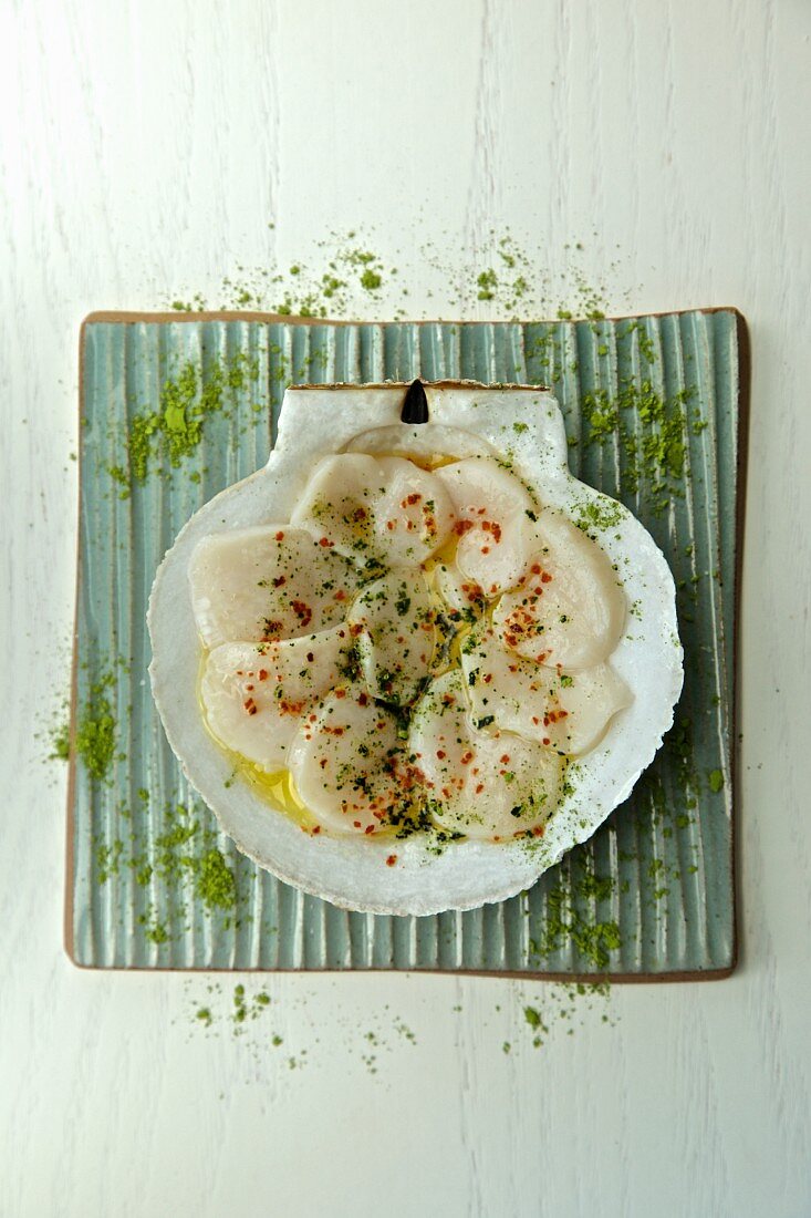 Raw sliced mussels with green tea in a scallop shell