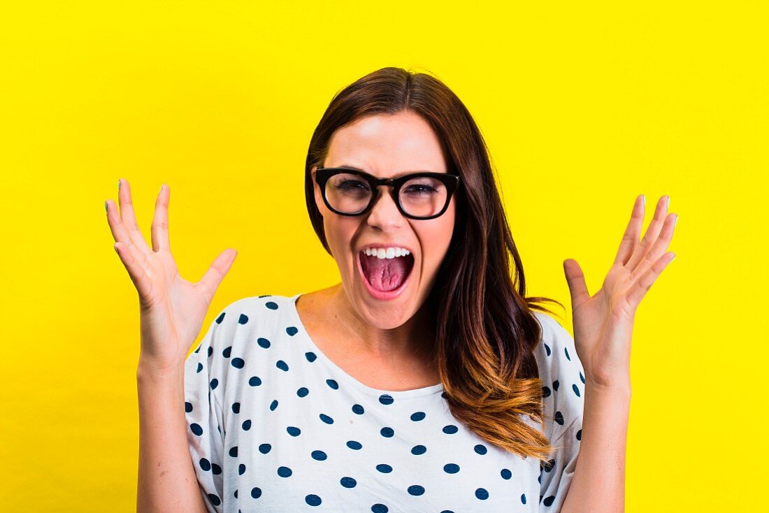 Schreiende Frau mit Brille und gepunktetem T-Shirt