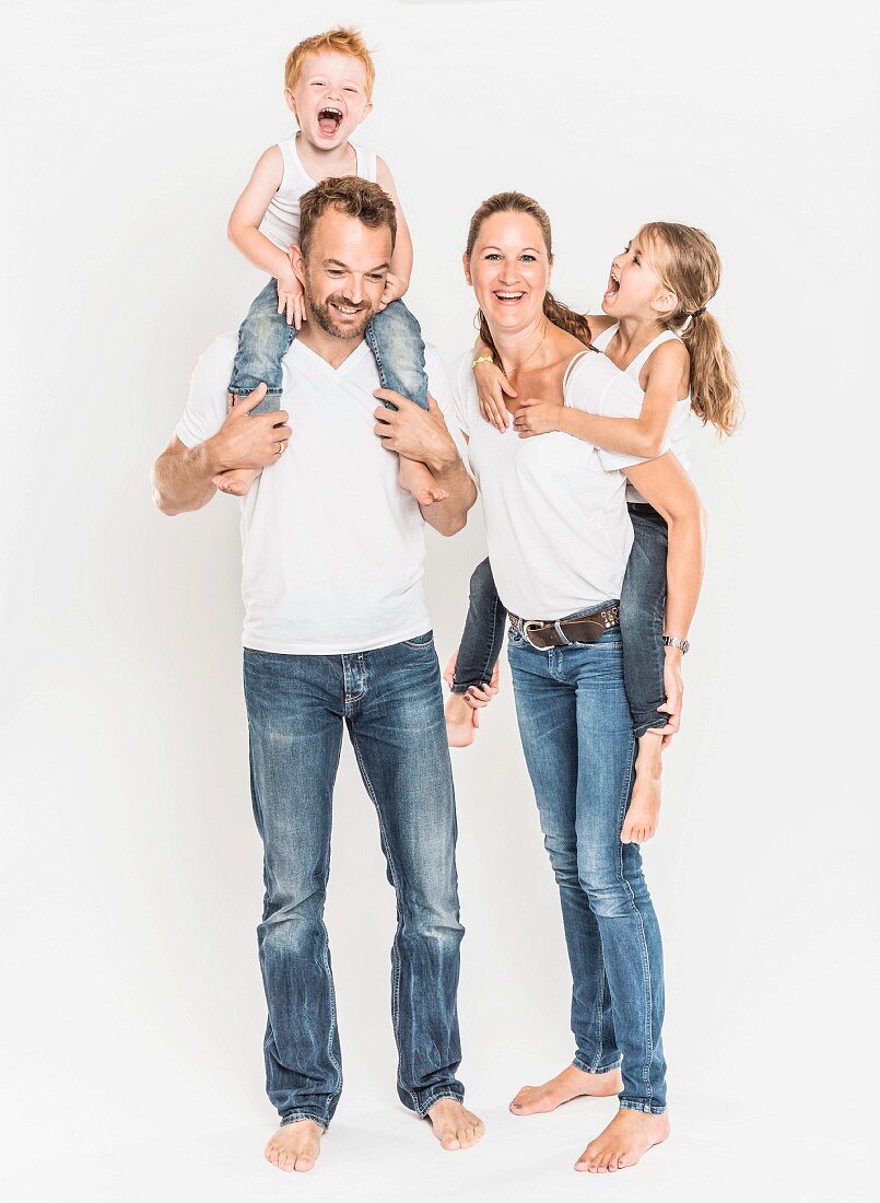 Familienportrait: Vater und Mutter tragen Sohn und Tochter Huckepack