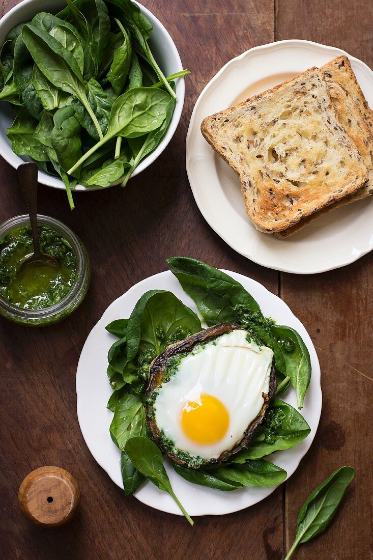 A fried egg on a mushroom on a bed of spinach with a parsley and garlic sauce