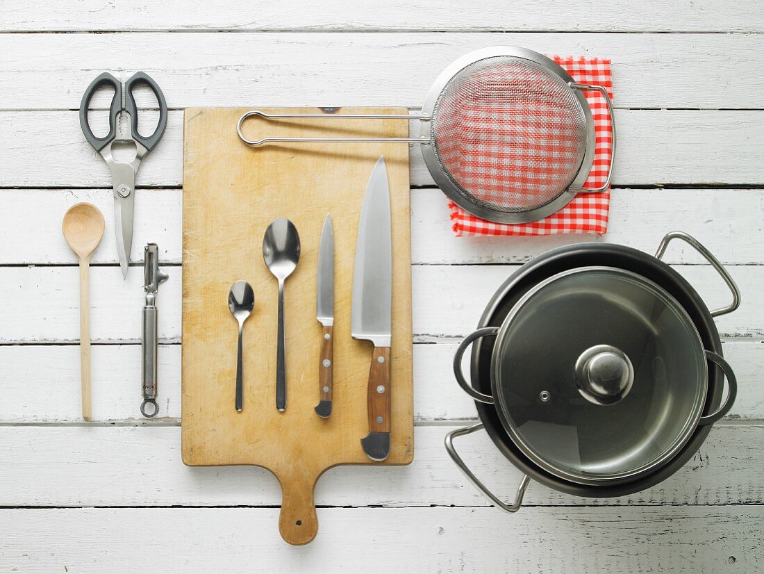 Kitchen utensils: pots, a sieve, knives, spoons, scissors and a peeler