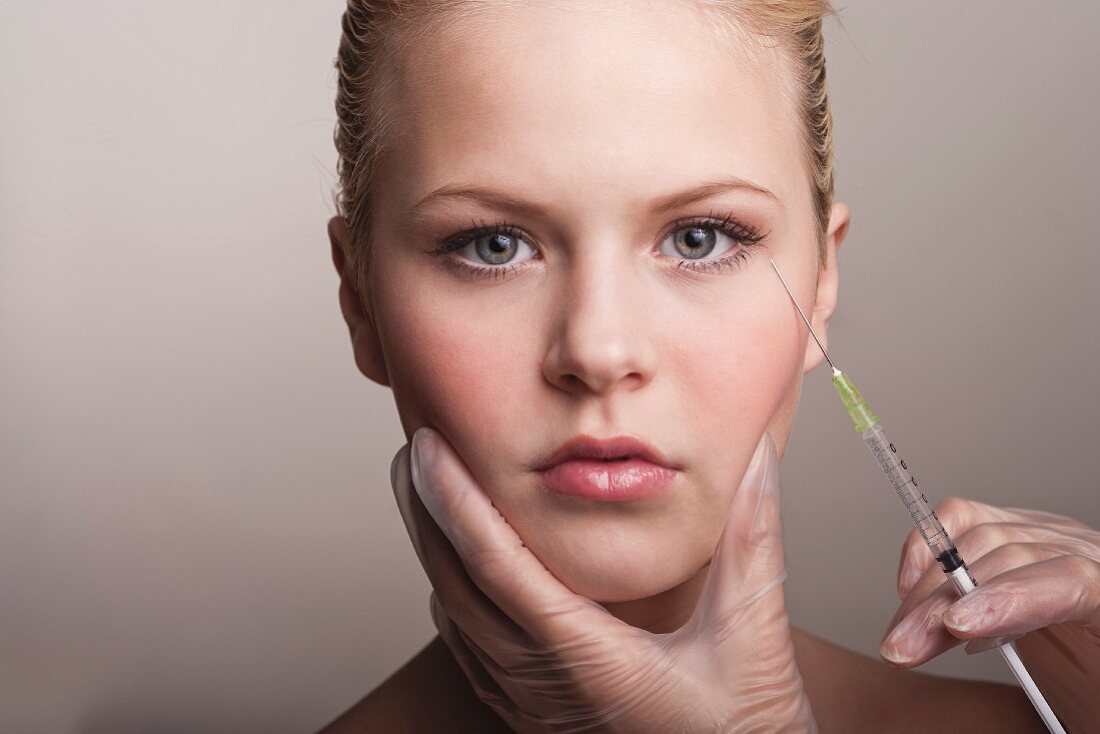 A young woman getting Botox injected into the area around her eyes