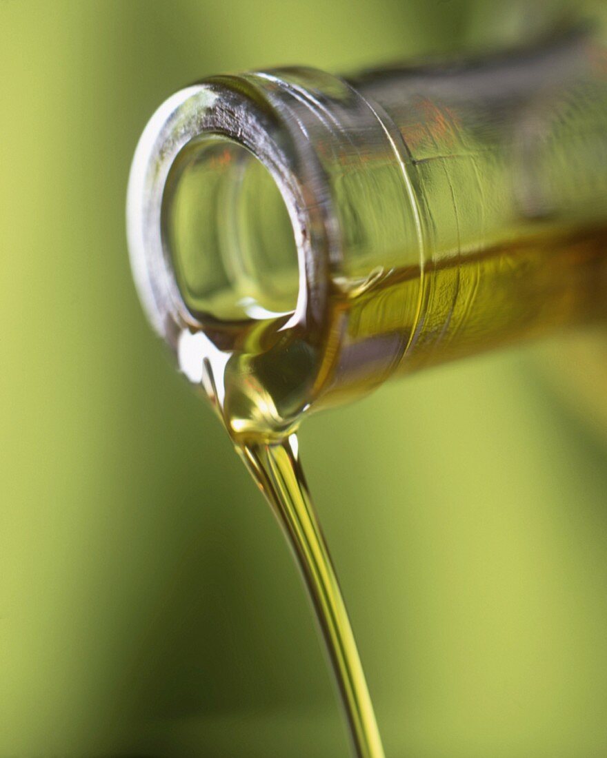 Olivenöl fliesst aus Flasche (Nahaufnahme)