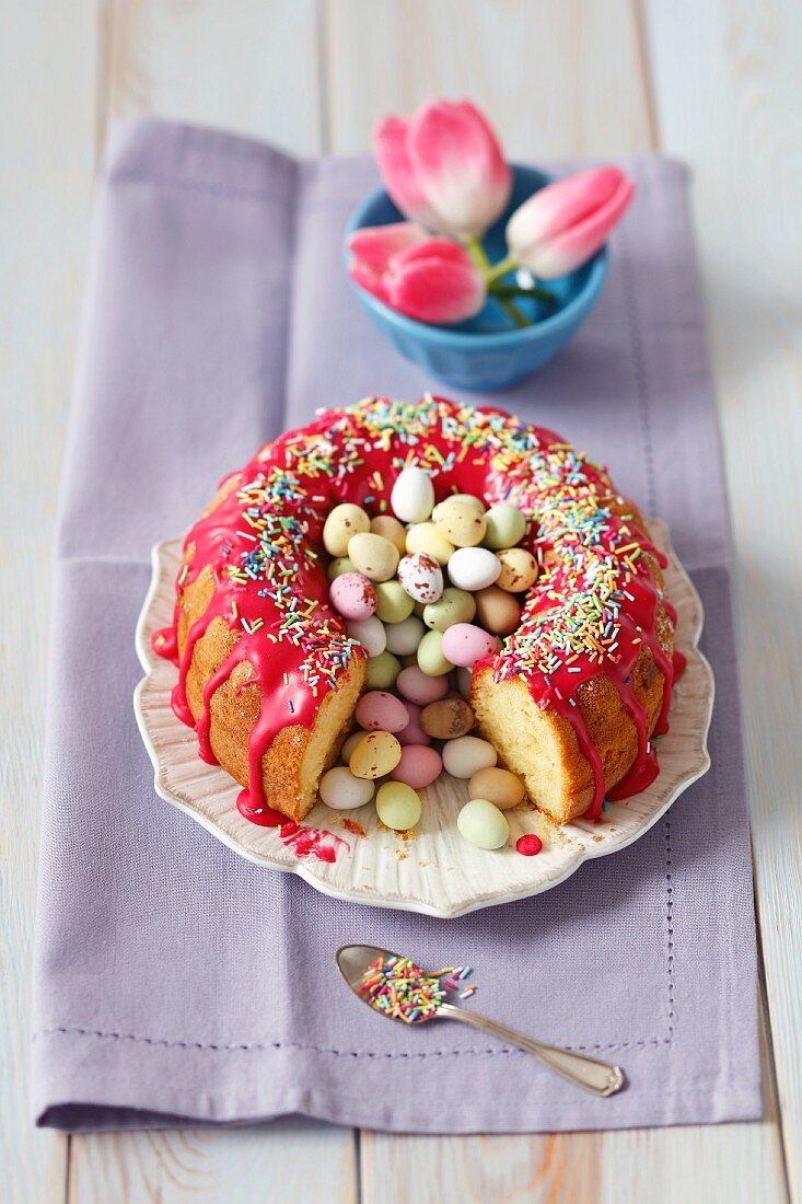 Lemon cake with red icing and colourful Easter eggs