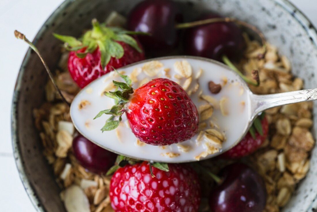 Muesli with strawberries, cherries and oat milk (seen from above, close-up)