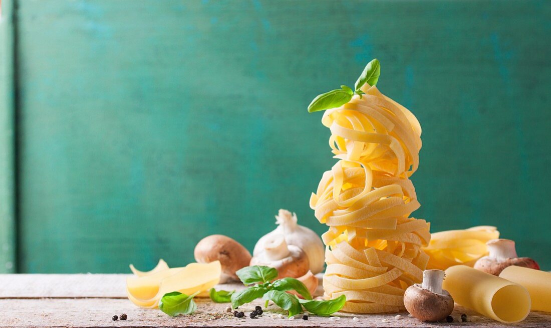 Tagliatelle mit Pilzen, Basilikum, Knoblauch und Pfeffer auf Holzbrett