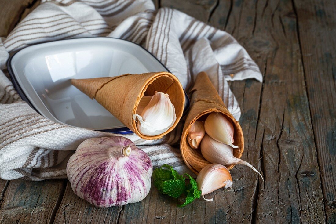 Purple garlic on a tea towel on a rustic wooden table