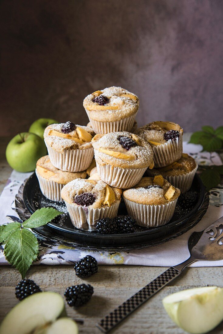 Blackberry and apple muffins stacked on a plate