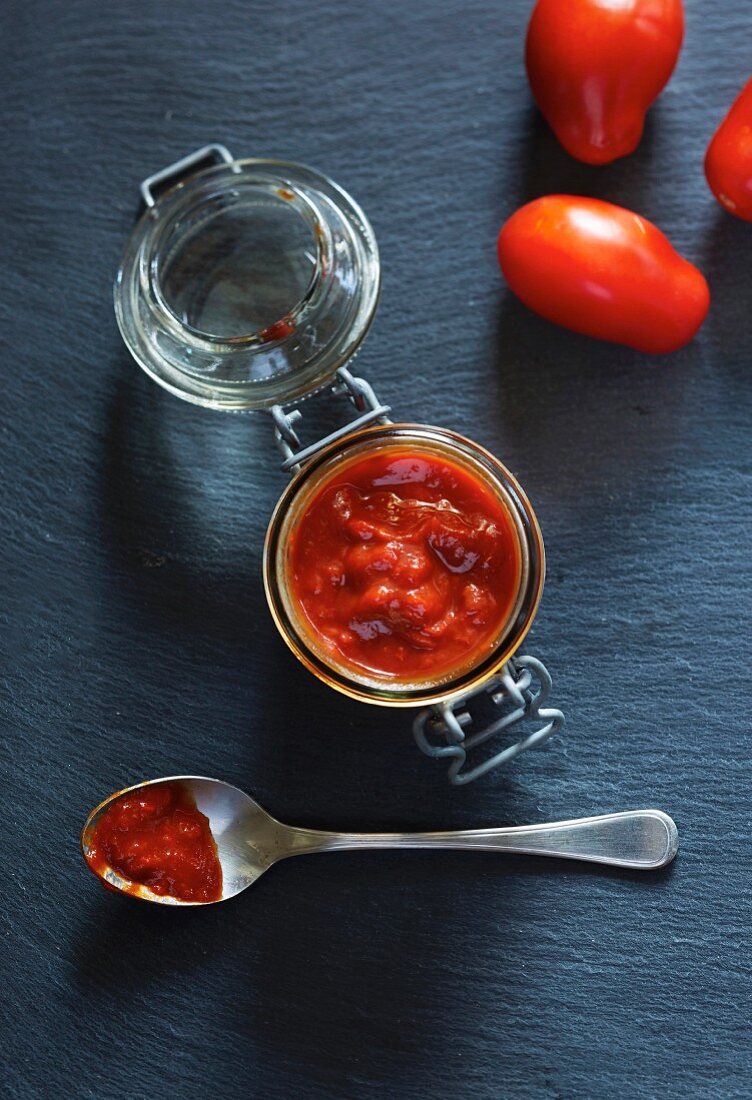 Home-made tomato ketchup on a spoon and in a jar