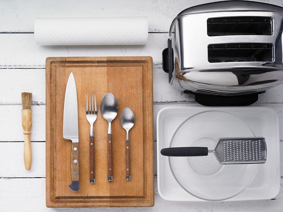 Küchenutensilien: Backpinsel, Messer, Besteck, Reibe, Auflaufform und Toaster