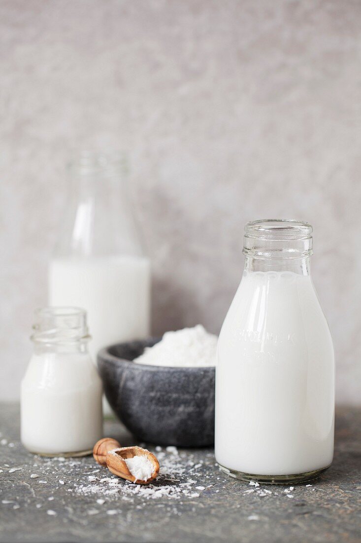 Three bottles of coconut milk and a bowl of desiccated coconut