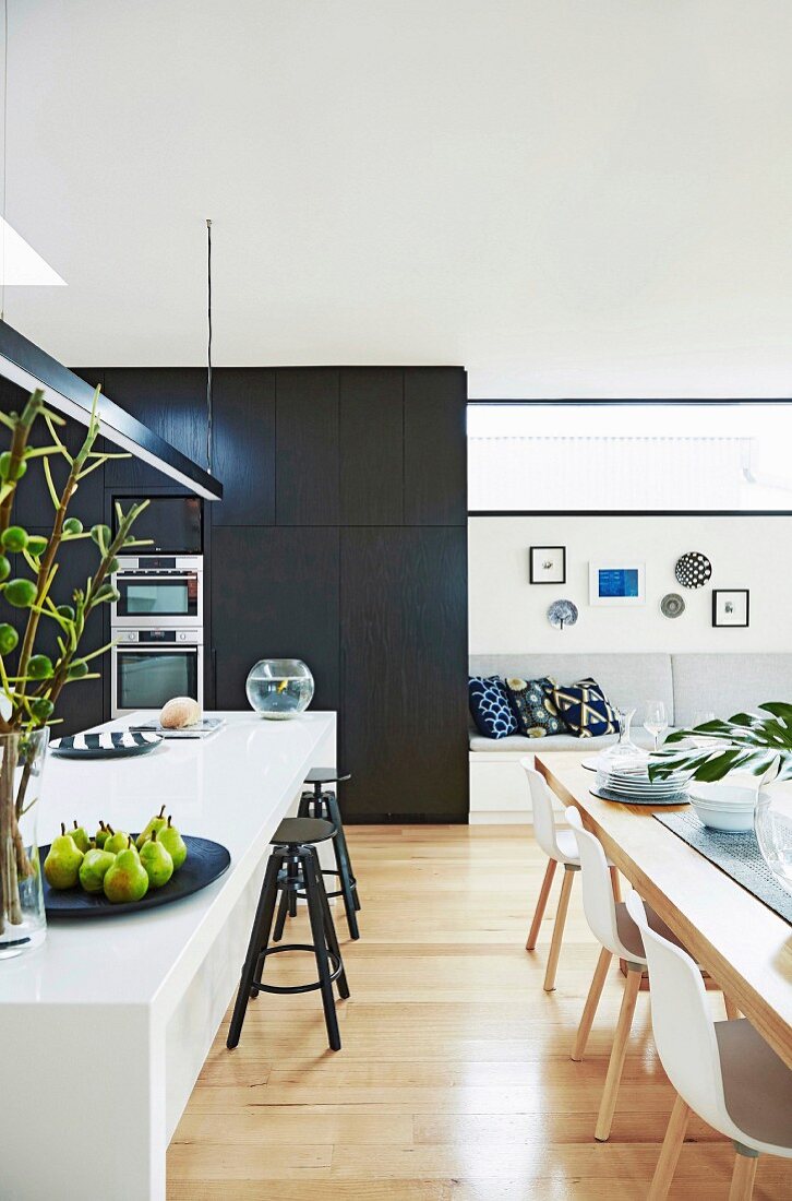 Open living room with kitchen island, dining table and upholstered bench