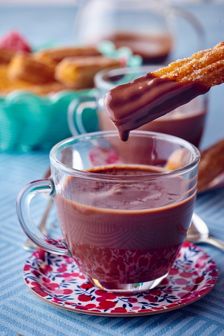 Churros being dipped in hot chocolate