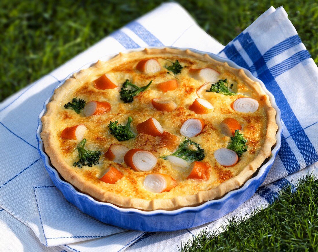 Quiche with surimi and broccoli in a baking dish on the grass