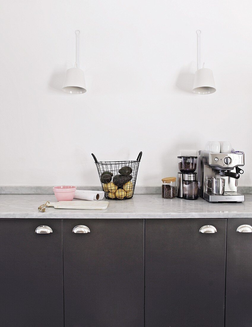 Sconce lamps above black kitchen cupboards with marble worksurface