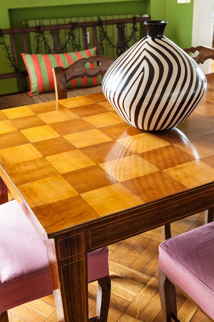 Black and white striped vase on wooden table with chequered top