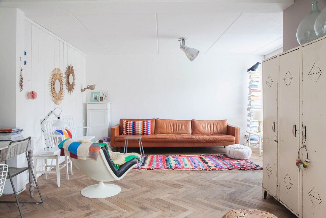 Leather couch, colourful rug and retro easy chair in living area