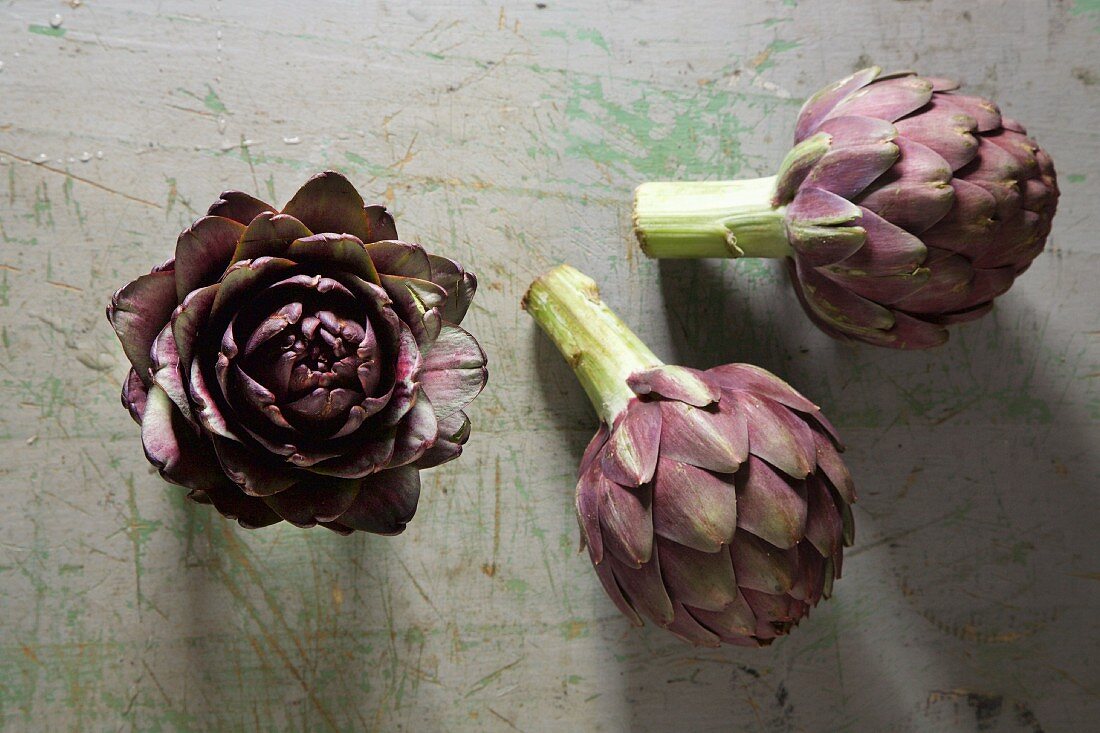 Three artichokes on a rustic surface