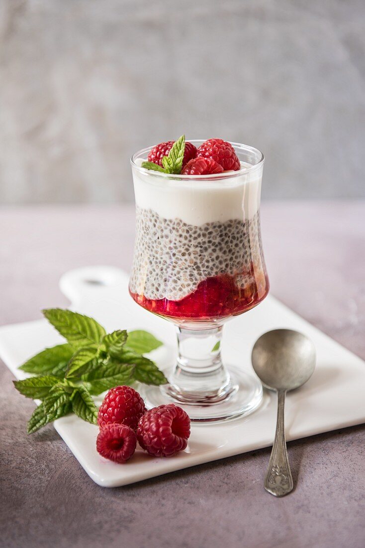 Chia pudding with raspberries and yoghurt in a dessert glass