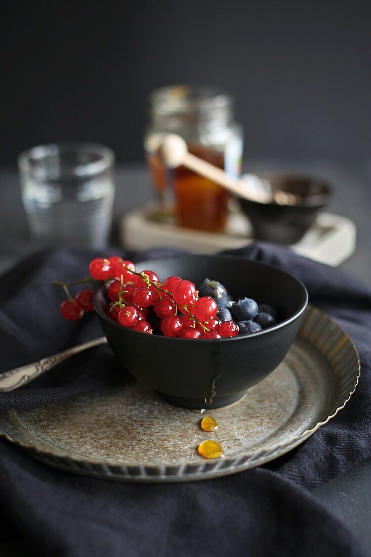 Fresh berries with honey in a dark bowl