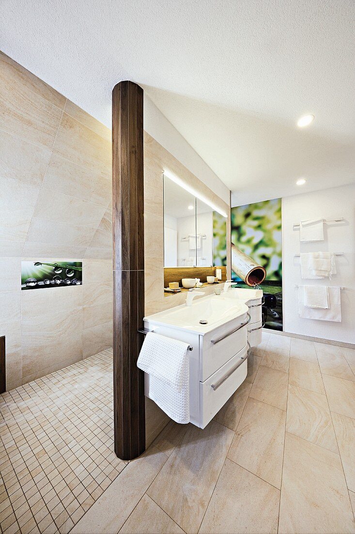 A curved white sink unit in an elegant designer bathroom with a shower area and photo art