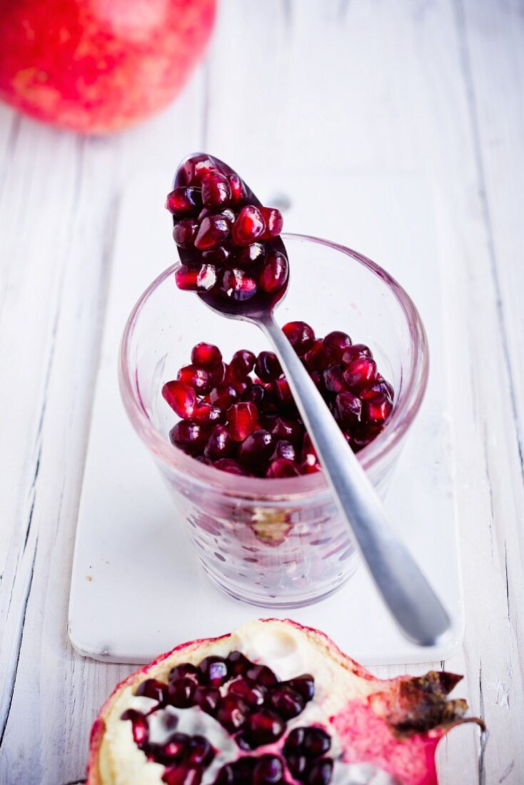 Pomegranate seeds in a glass and on a spoon