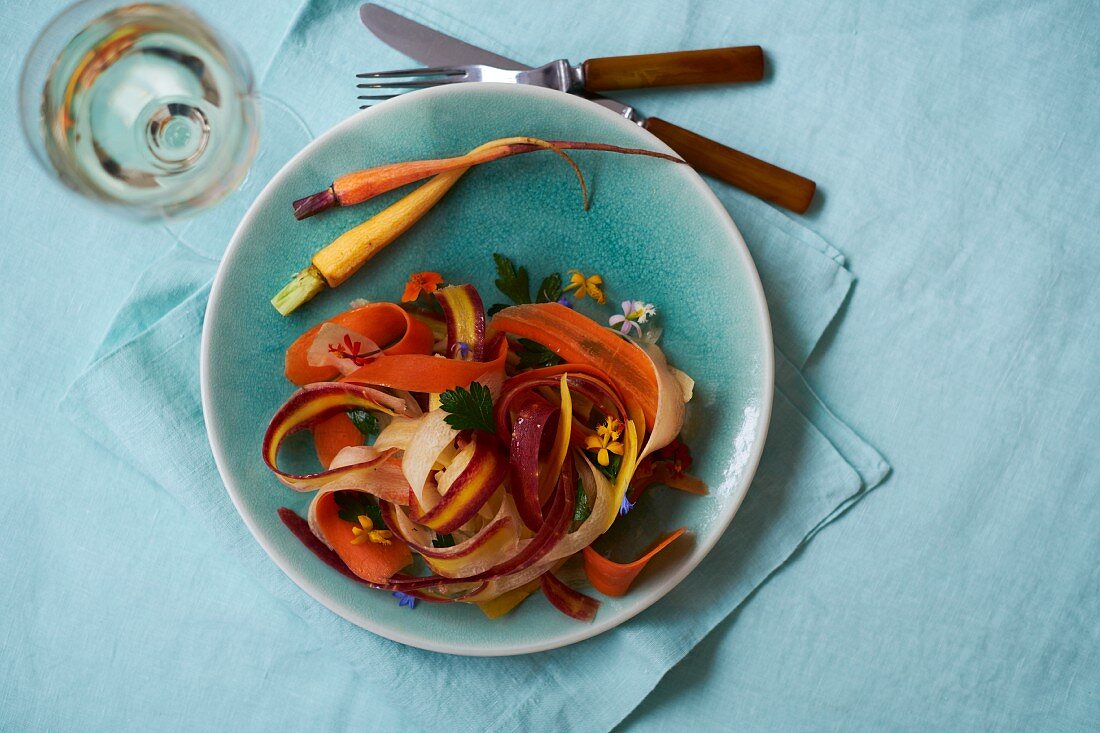 Different-coloured carrot pasta with edible flowers