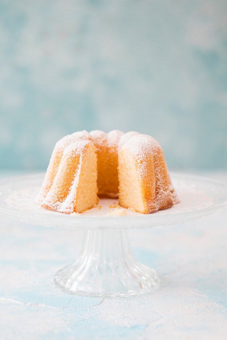 Lemon Bundt cake coated in icing sugar on a cake stand