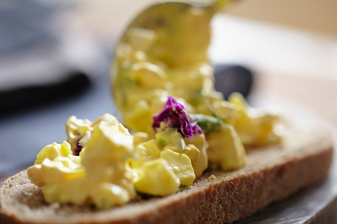 Egg salad with edible flowers on a slice of bread