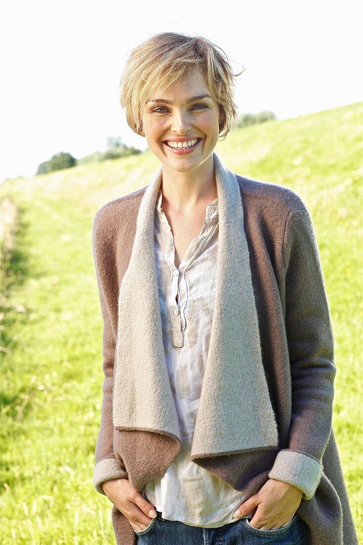 A young blonde woman wearing a natural coloured blouse and a woollen jacket