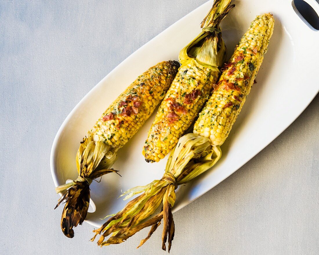 Grilled corn cobs with herbs, cheese and ham