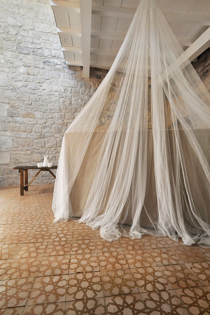 Mosquito net over bed in restored period building with Mediterranean ambiance