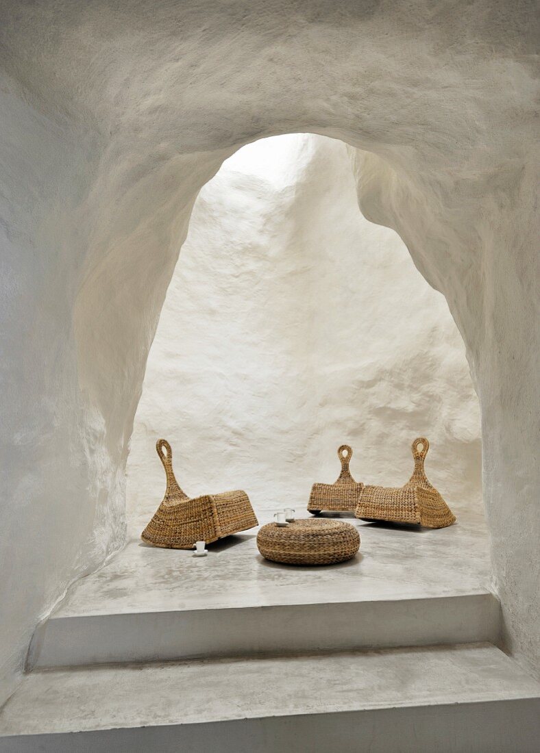 Wicker rocking chairs and low coffee table in unusual, white, cave-like lounge area