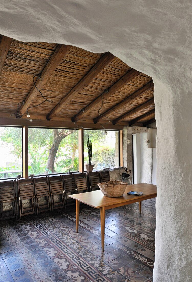 Wooden table, folded folding chairs and traditional tiled floor in Mediterranean dining area