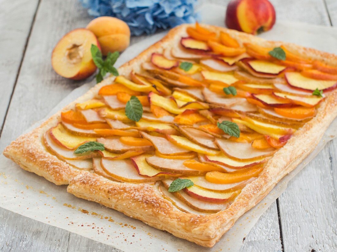 A fruit tart with slices of pear, peach, nectarine and apricot
