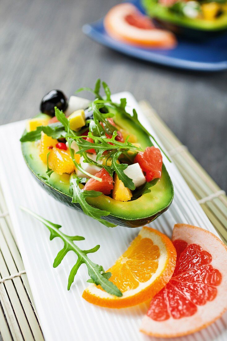 Avocado gefüllt mit Salat aus Zitrusfrüchten, Mozzarella, Oliven und Rucola