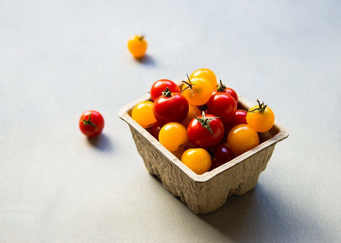 Red and yellow cherry tomatoes in a cardboard container