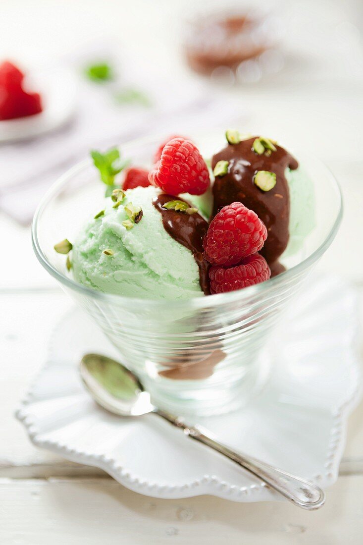 Pistachio ice cream topped with chocolate sauce and raspberries