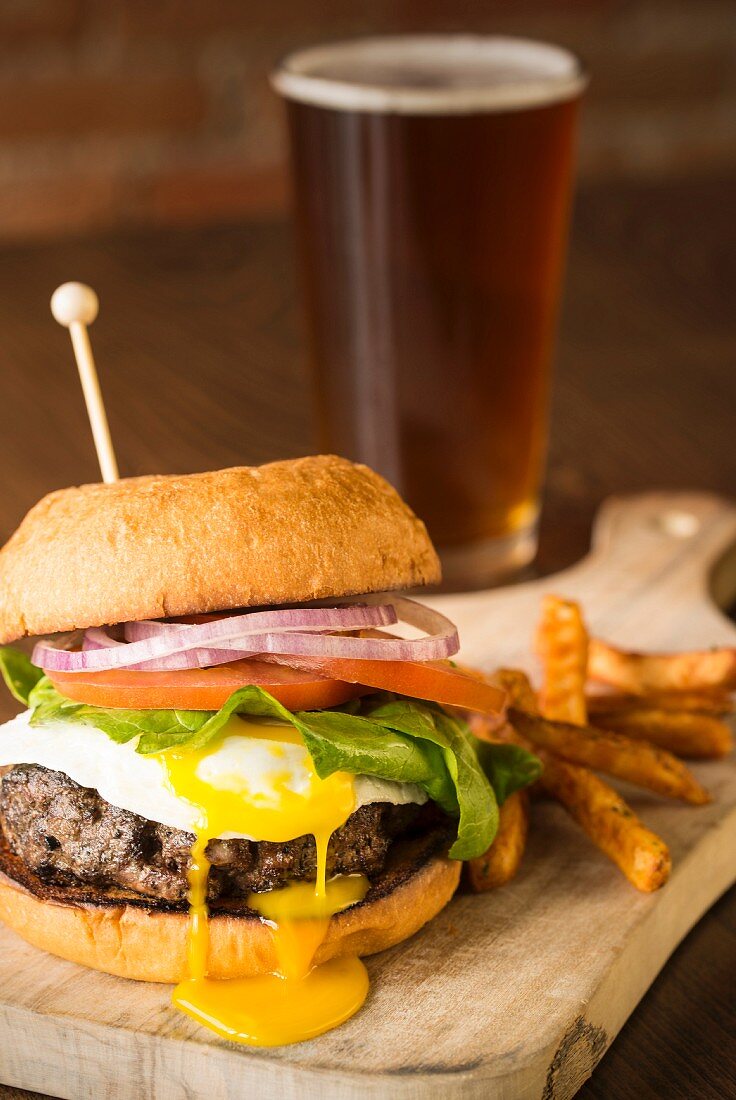 Burger mit Spiegelei, Pommes frites und Bier