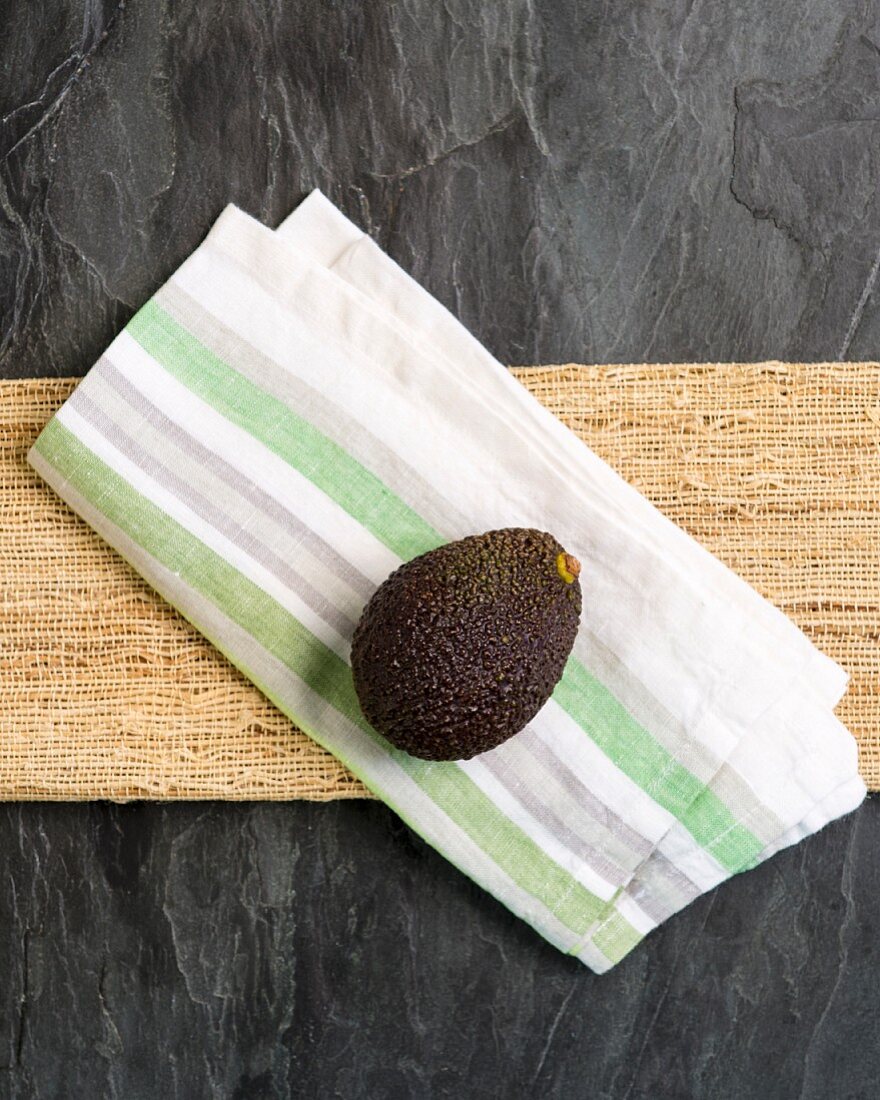 A whole avocado on a fabric napkin (seen from above)