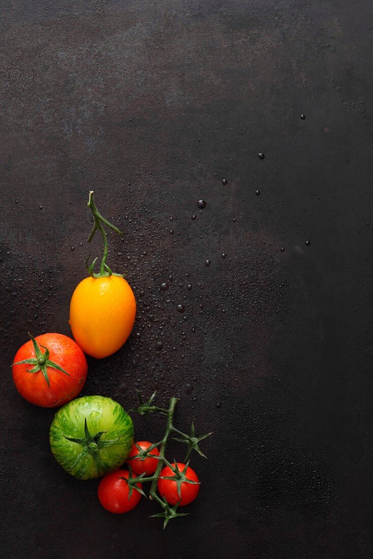 Various tomatoes on a black surface