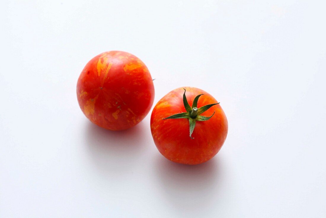 Zwei rote gestreifte Tomaten vor weißem Hintergrund