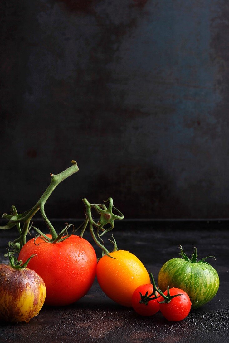 Various types of tomatoes on a black surface