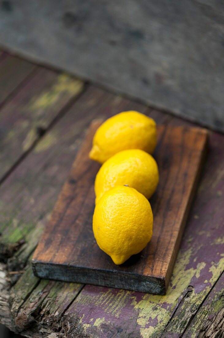 Three lemons on a wooden board