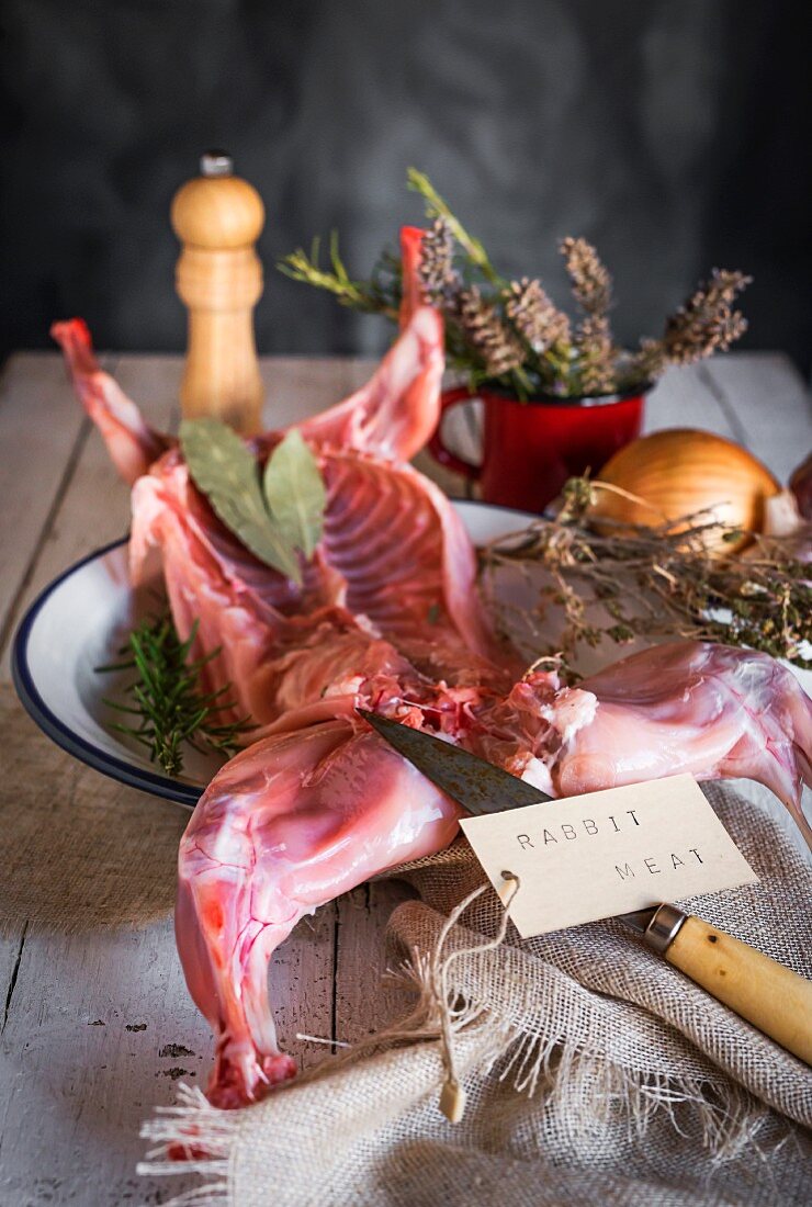 Rohes Kaninchen mit Kräutern und Gewürzen auf Holztisch