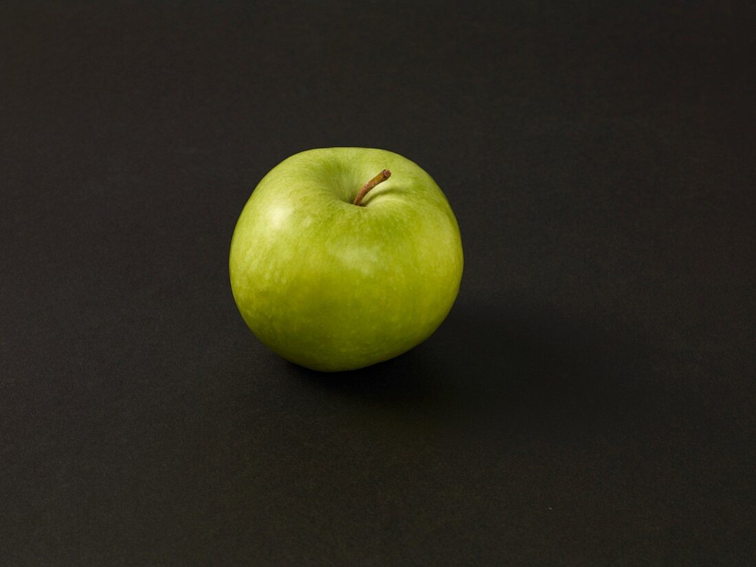 A green apple on a black surface