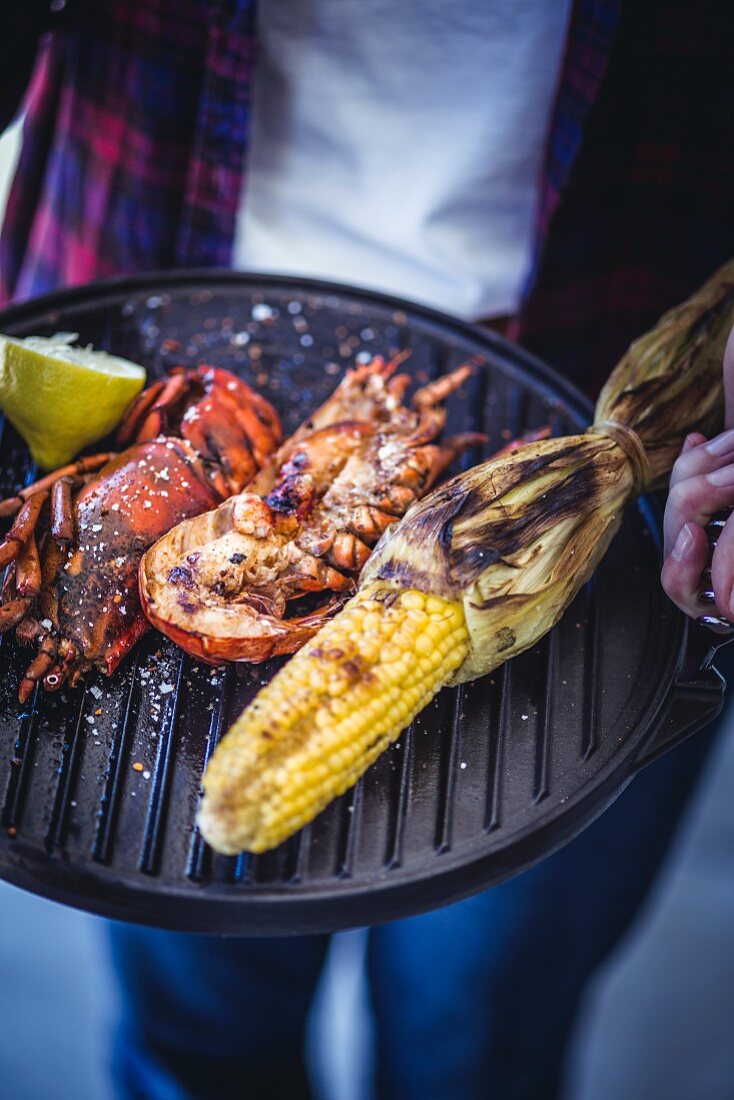 Grilled lobster and corn on the cob served on a barbecue griddle plate