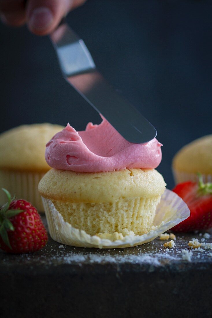 Decorating a cupcake with strawberry cream