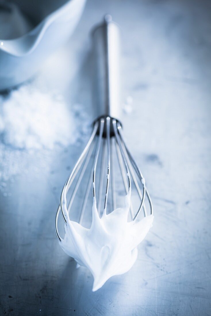 A whisk with whipped egg whites